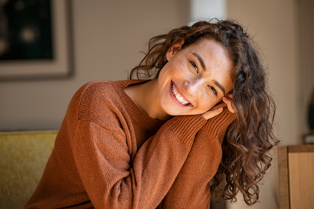Happy young woman sitting on sofa - Dental Fillings in Federal Way