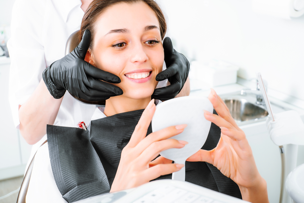 Woman checking teeth after a dental procedure - veneers Woman checking teeth after a dental procedure - veneers