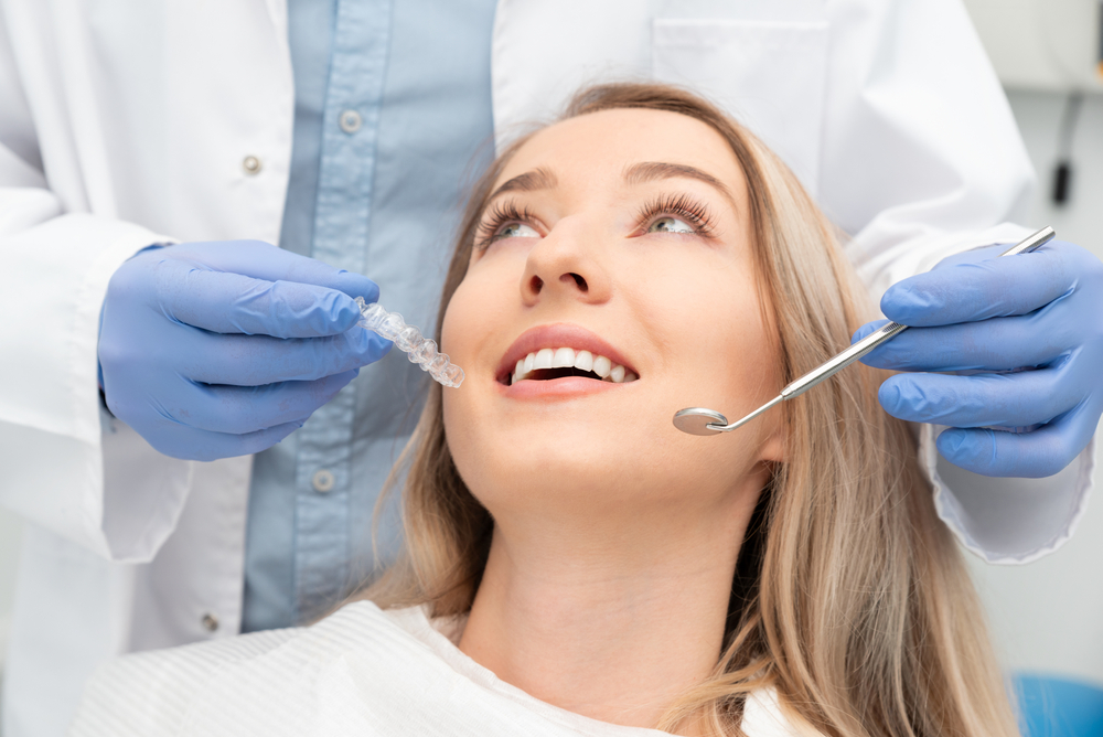 Woman receiving clear aligner consultation - Emergency Dentist in Bonney Lake A female patient looking up while a dentist presents a clear aligner during a dental checkup - Emergency Dentist in Bonney Lake