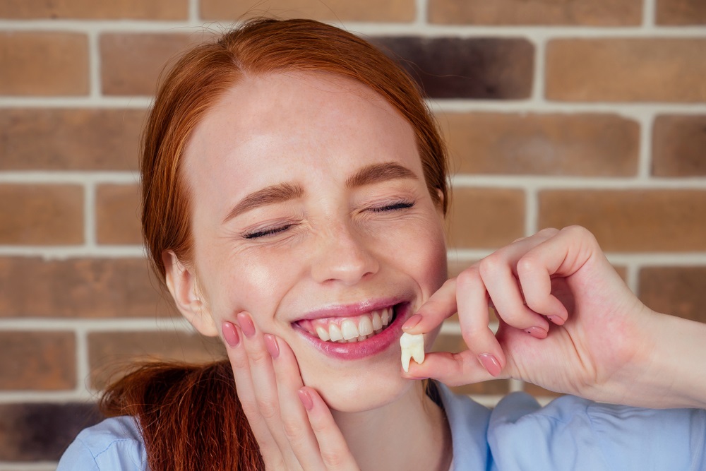 female with pain grimace holding white wisdom tooth after surgery - Tooth Extraction in Bellevue female with pain grimace holding white wisdom tooth after surgery - Tooth Extraction in Bellevue
